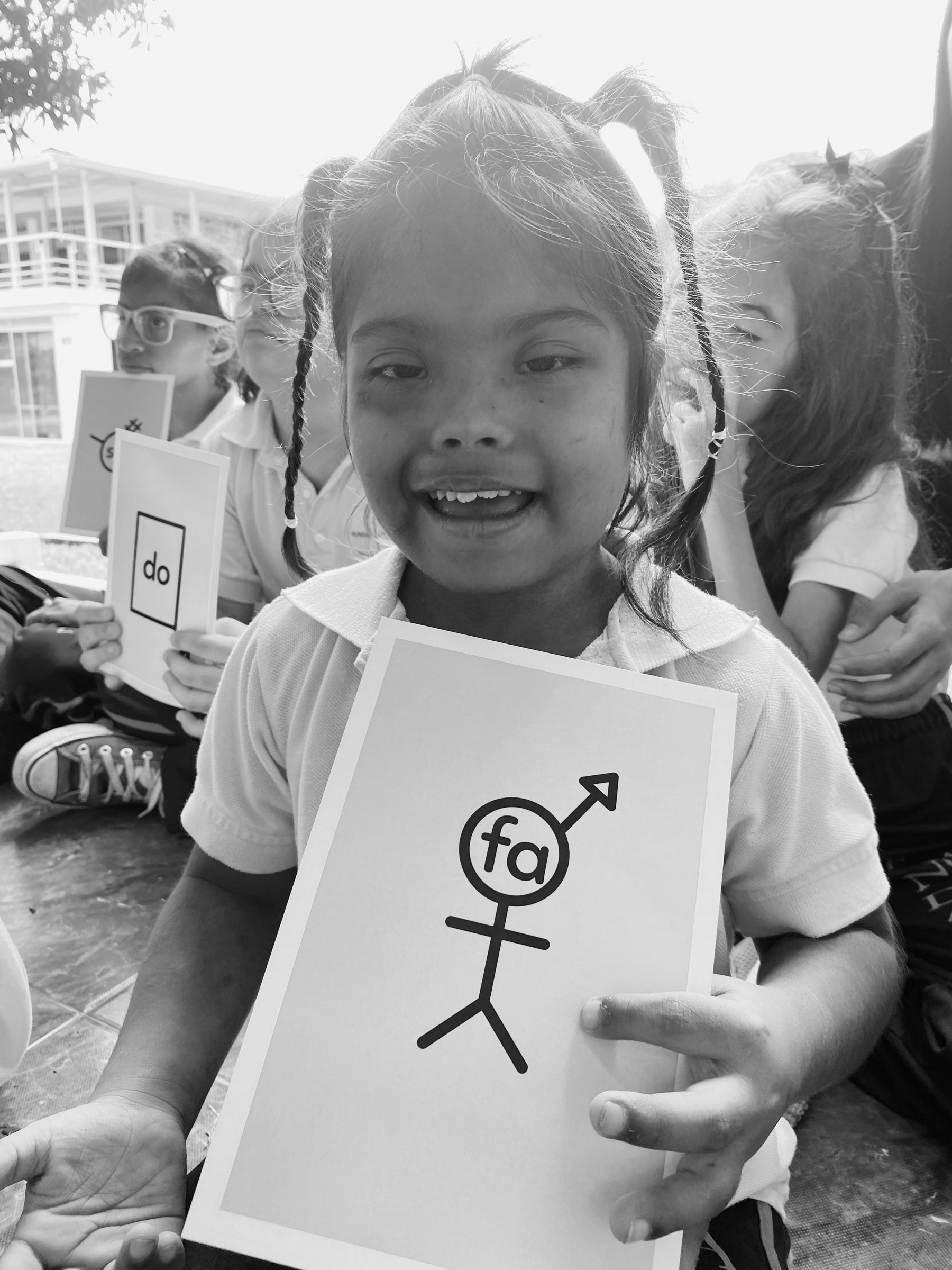 Una niña sonríe mientras sostiene una tarjeta del Método AMAR