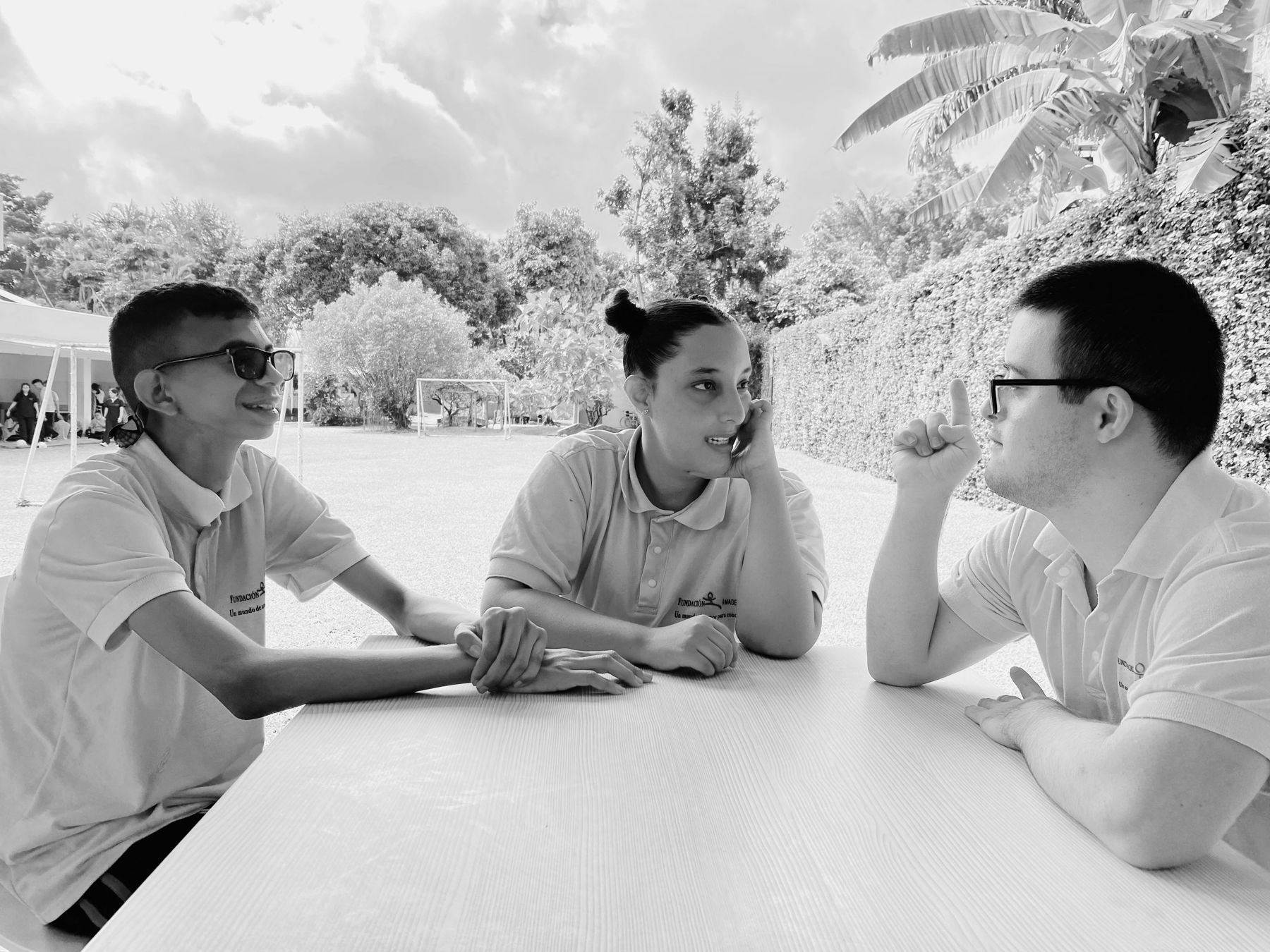 Tres estudiantes de la Fundación Amadeus conversan sentados alrededor de una mesa al aire libre