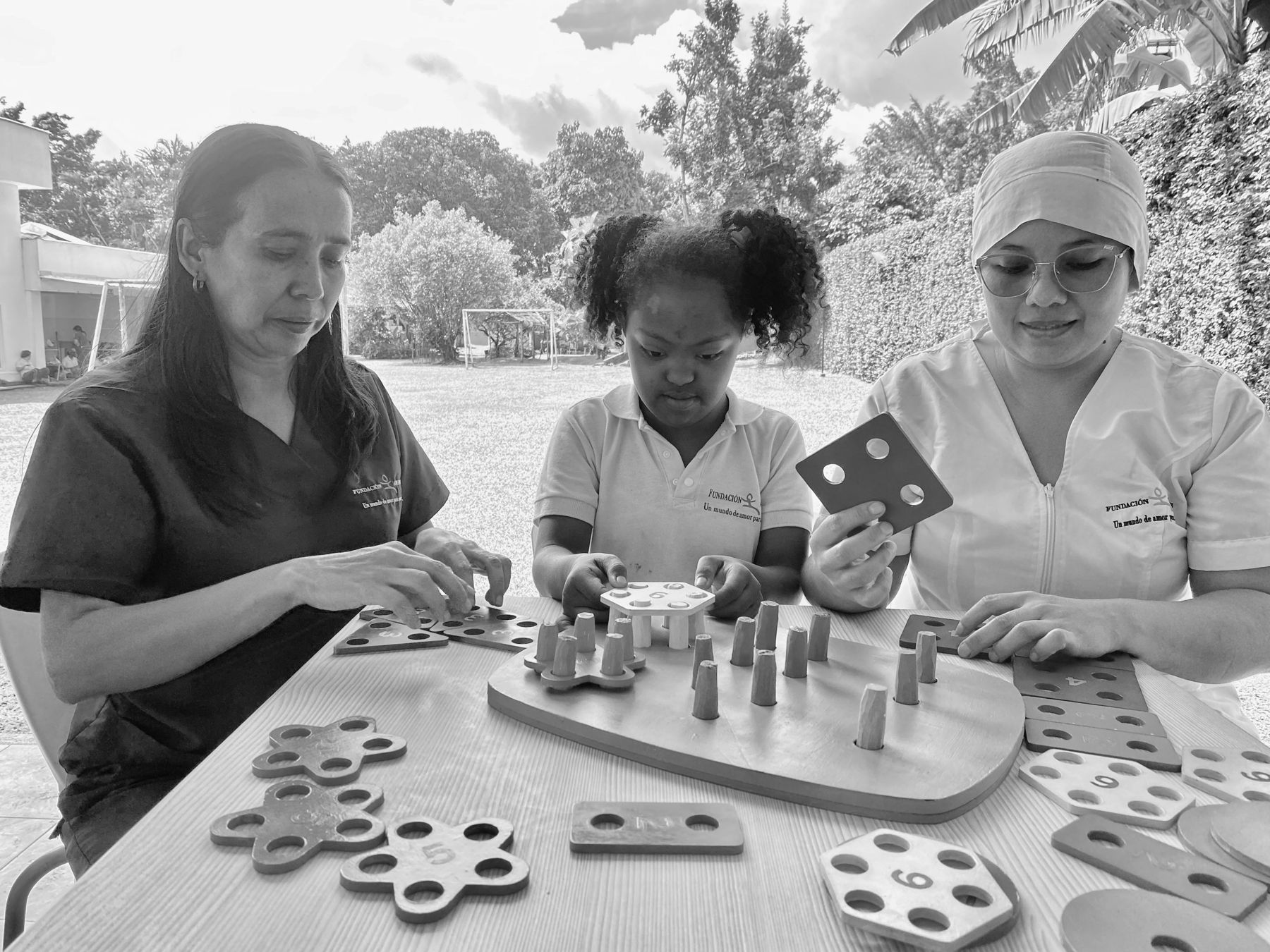 Una niña de la Fundación Amadeus trabaja con fichas numéricas junto a dos facilitadoras